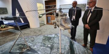 Representatives from French arms and military manufacturers stand near models of weapons at their stand during the 10th edition of the Baghdad security, defence and military industry fair organised on the premises of the Baghdad international exhibition complex in the Iraqi capital on March 2, 2022. (Photo by AHMAD AL-RUBAYE / AFP)