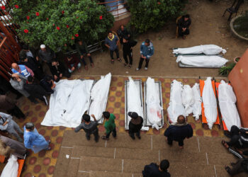 People stand near bodies of Palestinians who were killed during Israeli strikes on Ma'an school east of Khan Younis, at Nasser hospital, amid the ongoing conflict between Israel and Palestinian Islamist group Hamas, in Khan Younis in the southern Gaza Strip, December 5, 2023. REUTERS/Ibraheem Abu Mustafa